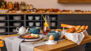 Een ontbijttafel met een theepot, kommen, een wijnglas en gebak.