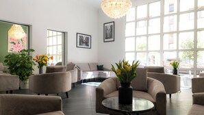 Een moderne zithoek met banken, een ronde tafel en potplanten.