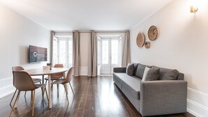A modern living room with a grey sofa, wooden dining table, and chairs.