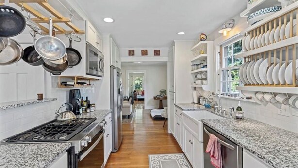 Une cuisine équipée d’une cuisinière, d’un four et de casseroles suspendues. On y trouve également un coin repas avec une table et des chaises.
