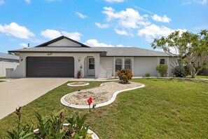 A modern two-story house with a garage numbered 417, surrounded by well-maintained lawns and a variety of plants.