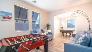 A cozy living room with a foosball table, a pool table, and a sofa. - Pool & Patio: Family-Friendly Goodyear Home! (Goodyear)
