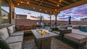 An outdoor patio with a fire pit, seating area, and a pool. - Pool & Patio: Family-Friendly Goodyear Home! (Goodyear)