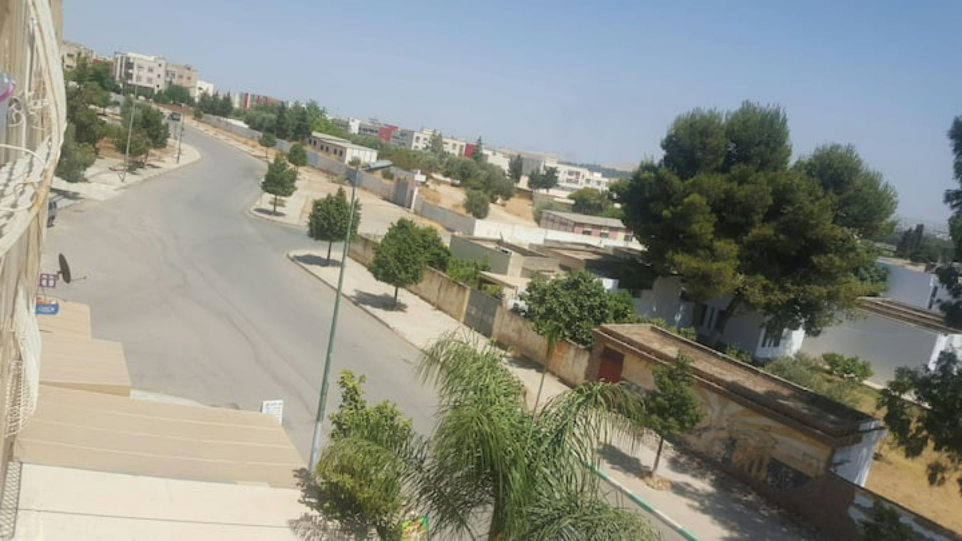 A residential area with a curved road, houses, and trees.