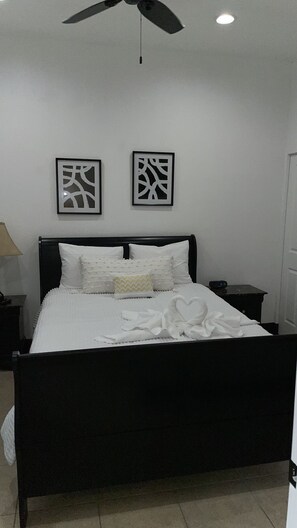 Cozy retreat with a black metal bed, ceiling fan, and wall-mounted lights.