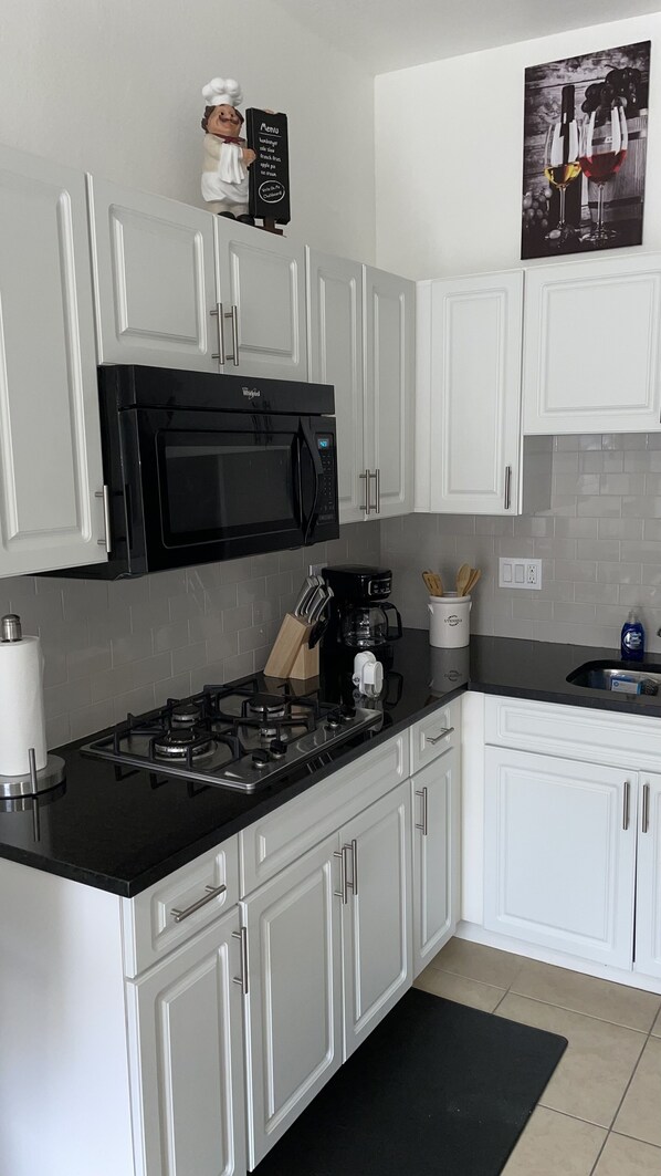 Enjoy cooking in this well-equipped kitchen with a stainless steel stove, microwave, and coffee maker.