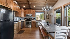 A kitchen with wooden cabinets, stainless steel appliances, a dining area with a bench, and large windows.