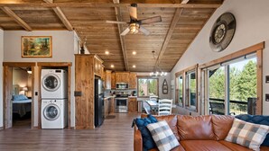 A spacious living area with a leather sofa, a kitchen with wooden cabinets, and a dining area with a table and chairs.