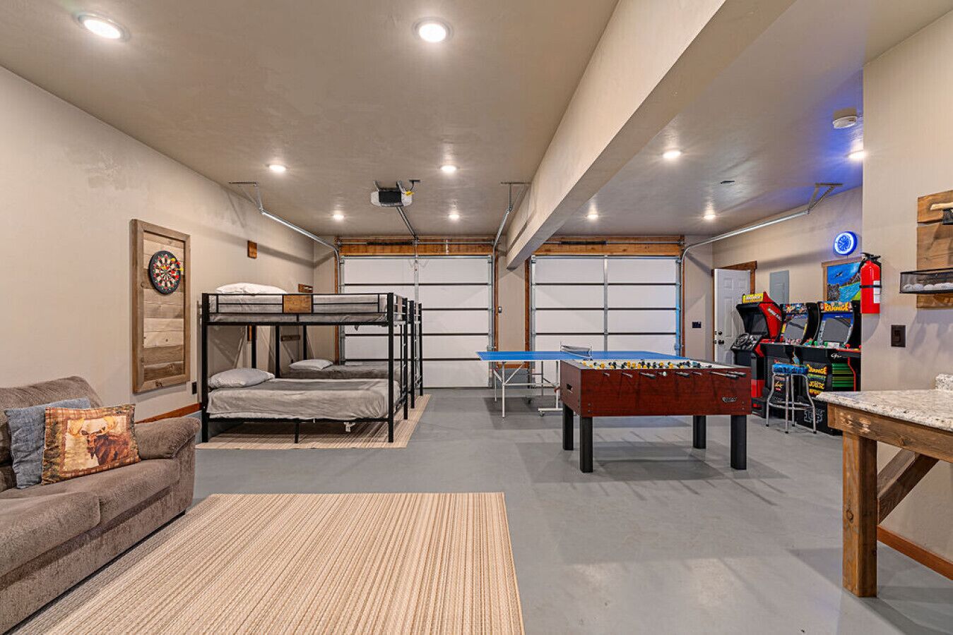 A room with bunk beds, a foosball table, and arcade games.