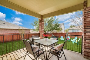 Relax in the serene outdoor space with a metal table and four chairs, surrounded by a brick wall and a wooden fence.