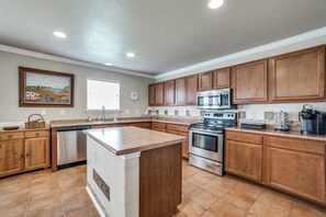 Enjoy cooking in this well-equipped kitchen with a central island, sink, and stainless steel appliances.