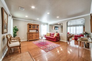 Relax in this inviting living room with a comfortable sofa and armchair, a wooden cabinet, and a dining area through the archway.