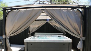 A hot tub under a covered area with a wooden fence in the background. - Budget-Friendly Retreat Stockyards HotTub MiniGolf (Fort Worth)