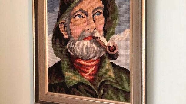 A framed cross-stitch artwork on a wall.