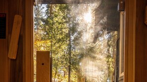 Una terraza de madera que conduce a una zona boscosa con un sendero de piedra.