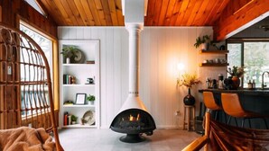 Una sala de estar acogedora con chimenea, techo de madera y una estantería.