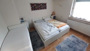 Een slaapkamer met een bed, een bureau, een radiator, een raam en een aan de muur hangend schilderij.
