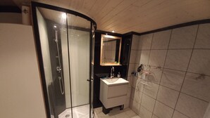 Een moderne badkamer met een douchecabine van glas, een wastafel en een spiegel.