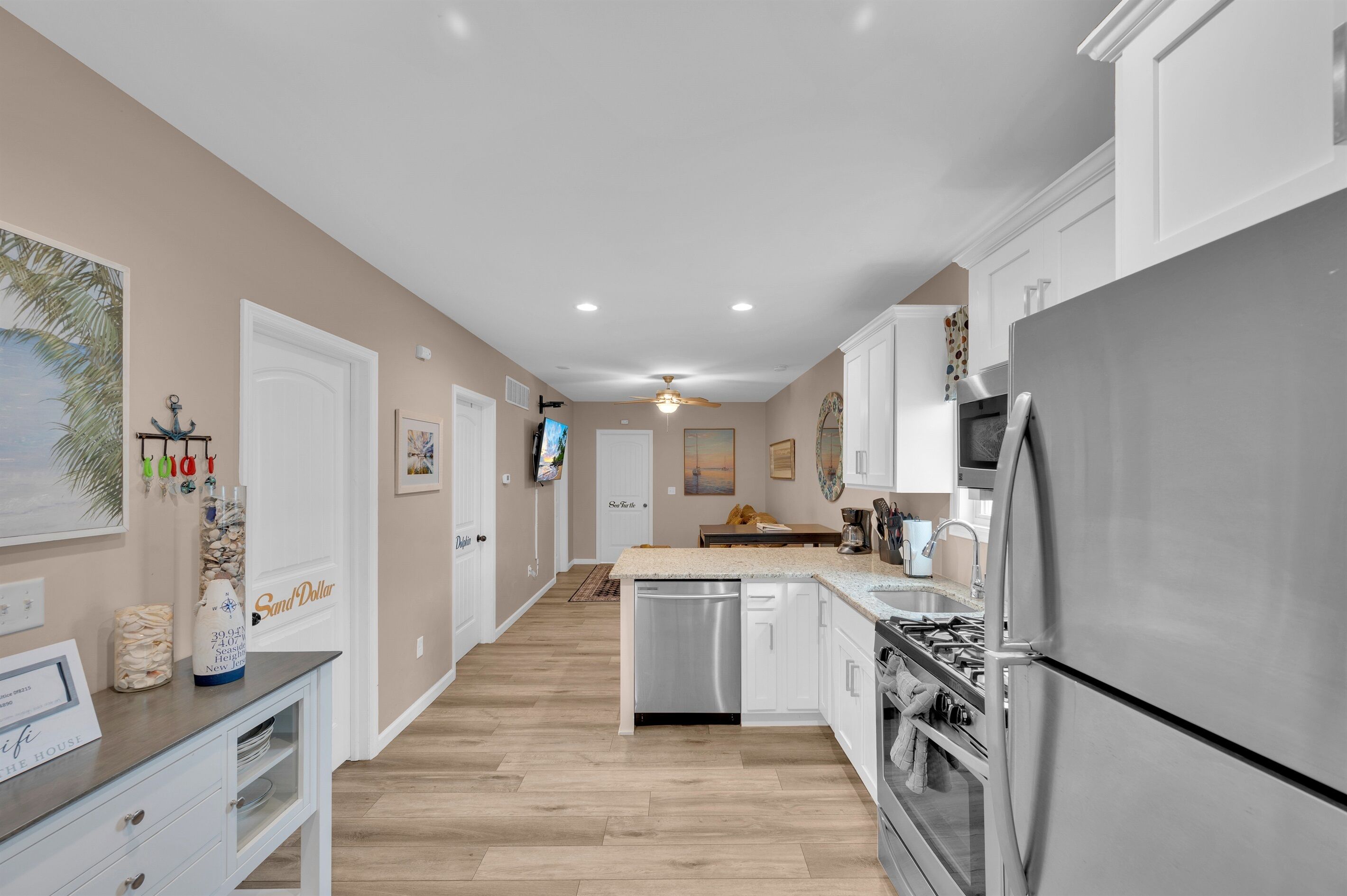Una cocina moderna con armarios blancos, electrodomésticos de acero inoxidable y suelo de madera.