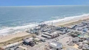Vue aérienne d’une zone côtière avec des bâtiments, une plage et l’océan.