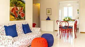 Una sala de estar con sofá, reposapiés y un comedor con sillas y una mesa.