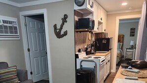 Een compacte leefruimte met een kitchenette, een bank en een eethoek met geweven placematen.