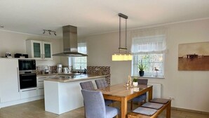 Una cocina moderna con una isla central, electrodomésticos integrados y un comedor con mesa y sillas de madera.