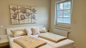 Un dormitorio con cama, ventana y una obra de arte en la pared.