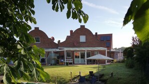 A house with a brick exterior, a covered patio, and a small pond with a boat.