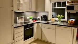 A modern kitchen with white cabinets, a black countertop, and stainless steel appliances.