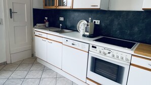 Une cuisine avec des armoires blanches, une cuisinière Bosch, une machine à café et un évier.