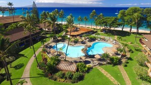Ein Resort mit großem Pool, Palmen und Blick auf den Strand.