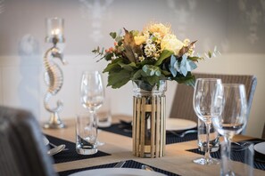 Una mesa de comedor con un centro de flores, vasos transparentes y un candelabro.