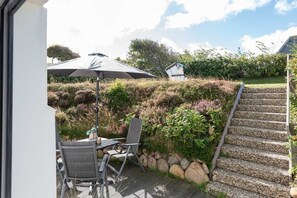 Eine Terrasse mit Gartenmöbeln, einem Tisch und einem Sonnenschirm.