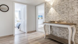 Ein Flur mit Holzboden, einer weißen Tür und einer Wand mit floralem Muster.