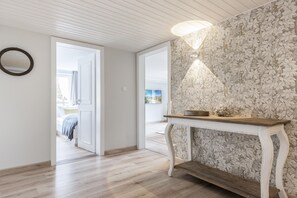 Ein Flur mit Holzboden, einer weißen Tür und einer Wand mit floralem Muster.