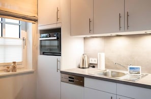 A modern kitchen with a built-in oven, a coffee maker, and a sink.