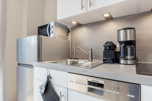 Et moderne køkken med stålemmer, en indbygget vask og kaffemaskine.