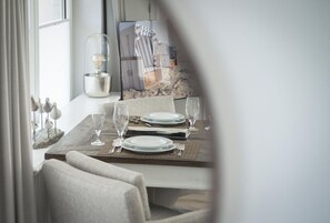 Une table à manger dressée avec des assiettes, des verres et des couverts, agrémentée d’une sculpture d’oiseau décorative et d’un tableau encadré accroché au mur.