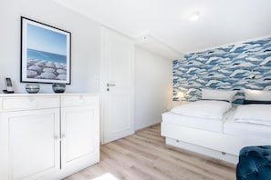 Un dormitorio con una cama, una mesita de noche, una lámpara de pared y un cuadro enmarcado sobre la cama.
