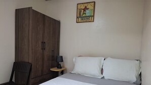 Una camera da letto con un letto, un armadio in legno, un tavolino con una lampada e una decorazione a parete.