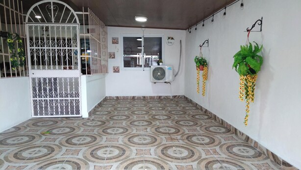 Una stanza con piastrelle decorate, un cancello bianco, un condizionatore d'aria e piante pensili.