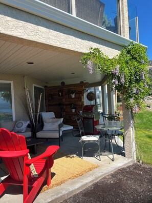 A covered patio area with outdoor seating, a grill, and a view of the surrounding landscape. - Legal 1 bedroom Guest Suite for two, with lake views & walk to wineries.  (West Kelowna)