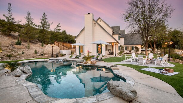 Ein Garten mit Swimmingpool, Sitzgelegenheit im Freien und einem Haus.