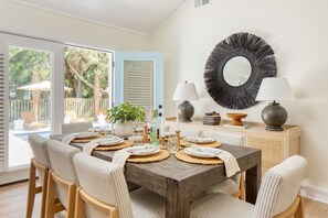 A dining area with a wooden table set for six, surrounded by cushioned chairs. - Sawyer by AvantStay | Stunning Isle Of Palms Home w/ Pool! (Isle Of Palms)