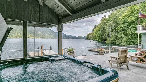 Un jacuzzi en una terraza con vistas a un lago y montañas.