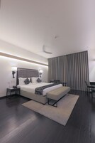 A modern hotel room with a large bed, bedside tables, a desk, and a chair.