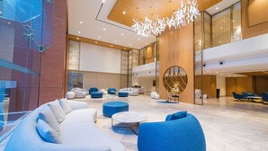 Un hall d’entrée spacieux, doté de mobilier moderne, d’un grand lustre et d’un plafond haut.