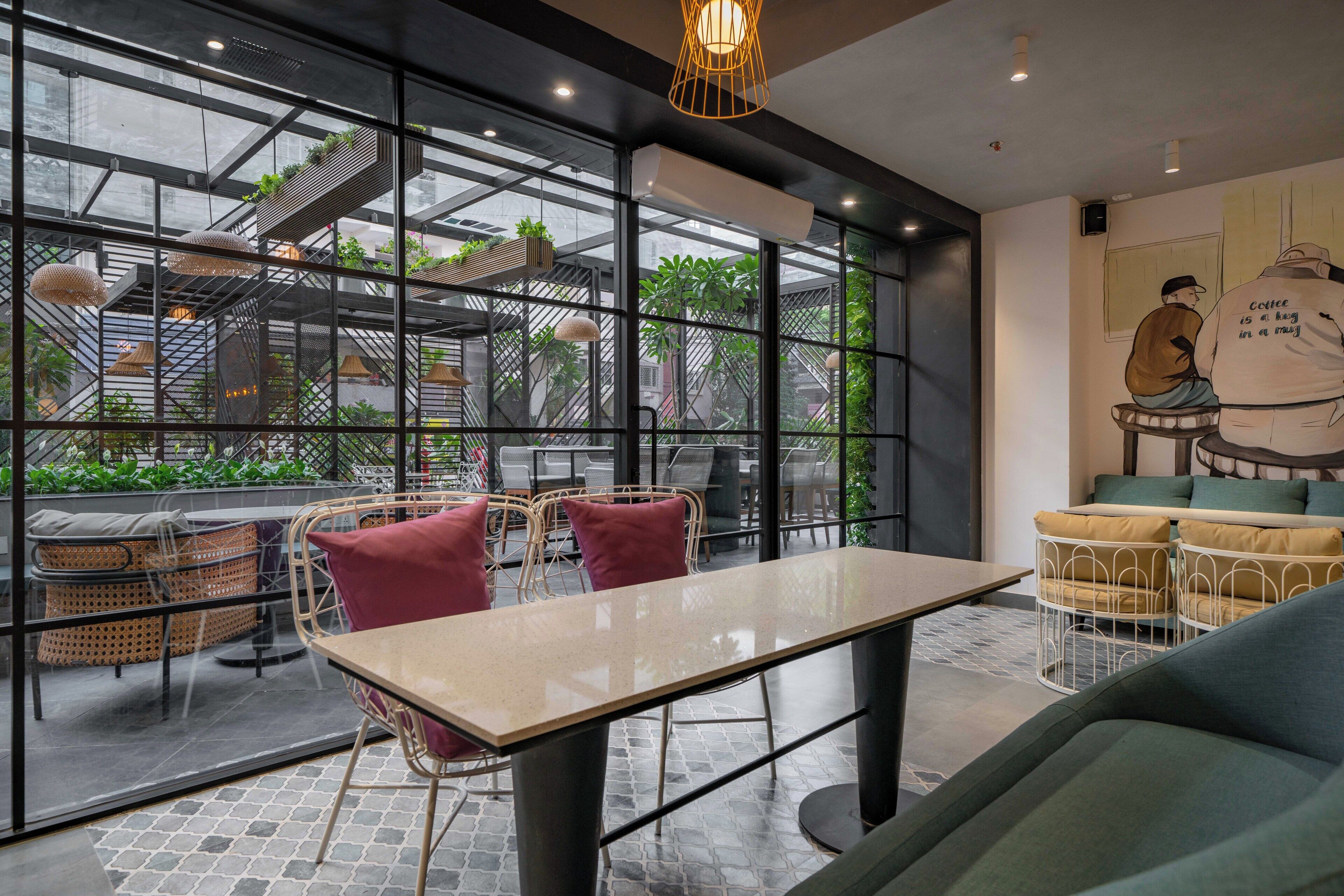 A modern cafe with a glass wall, wicker furniture, and a mural.
