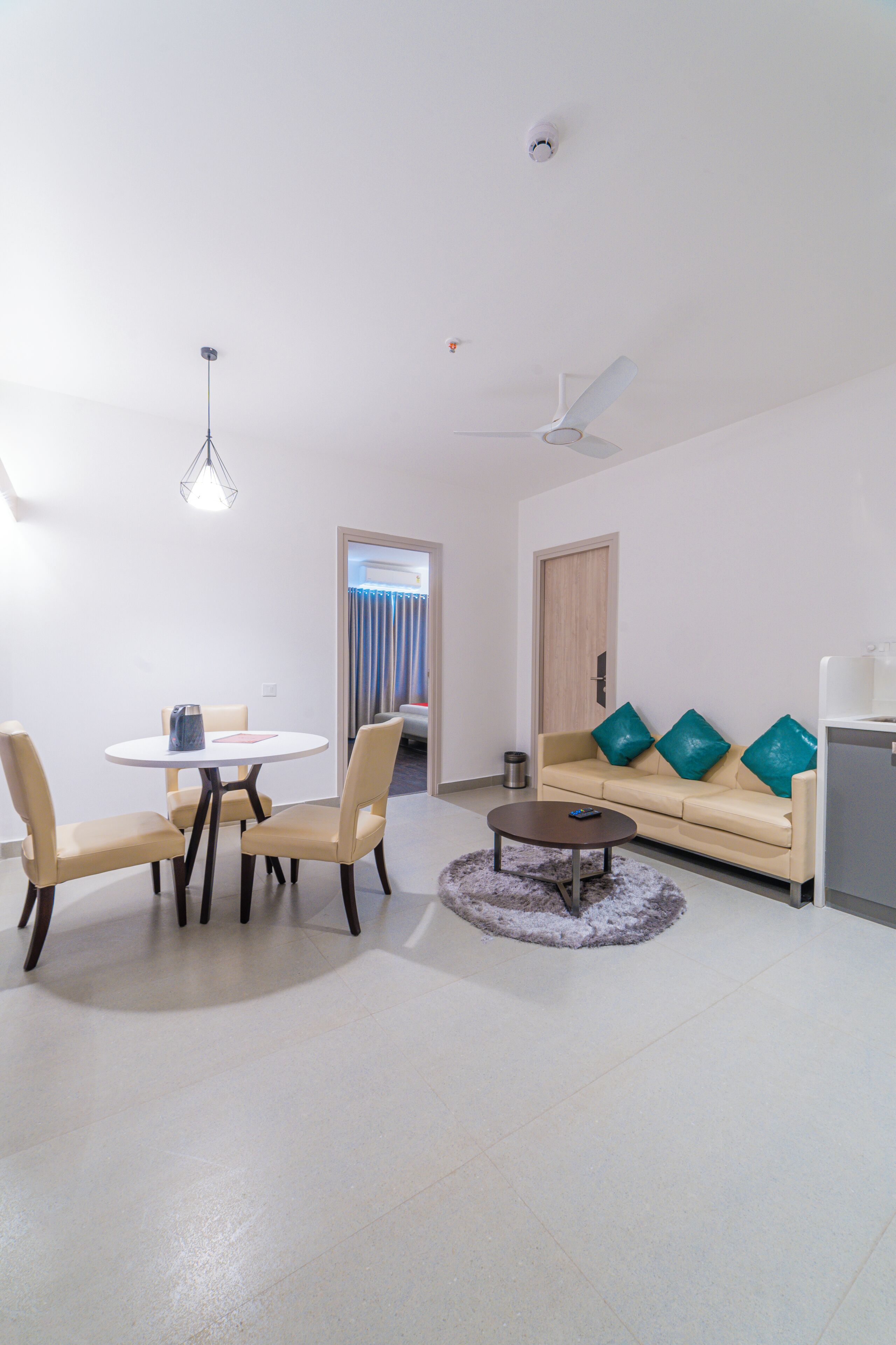 Un salon moderne avec une table à manger ronde, un canapé beige et un ventilateur de plafond.
